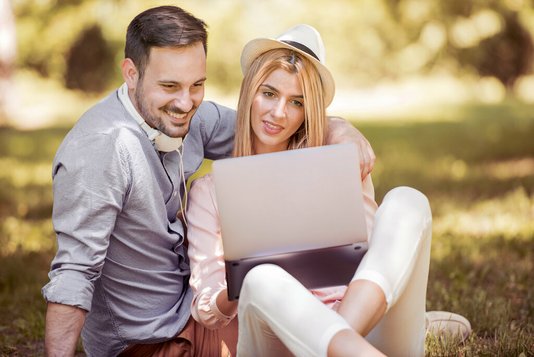 menschen-gemischt-paar-laptop-wiese Junges Paar vor dem Laptop